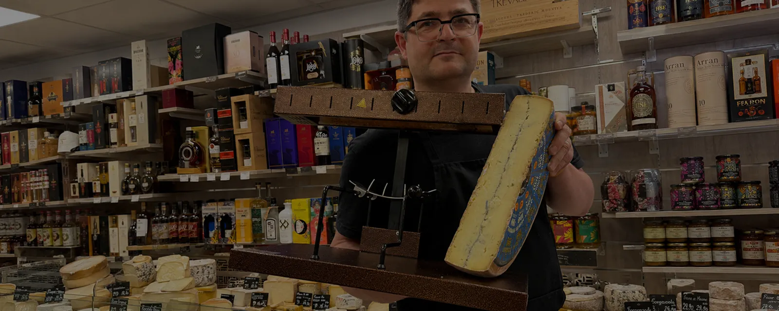 Caviste pr&eacute;sentant un grand bloc de fromage dans une &eacute;picerie fine