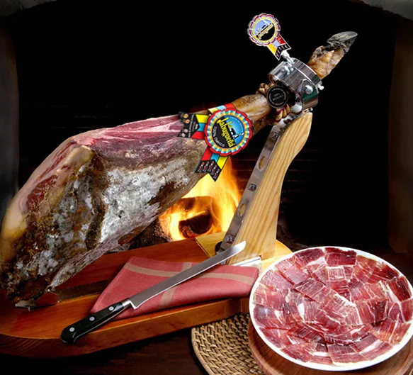 Jambon ibérique suspendu et tranches sur planche en bois.