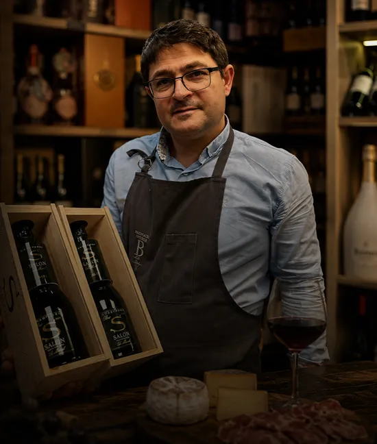 Christophe, caviste, présente des bouteilles de vin et fromages dans son épicerie fine.